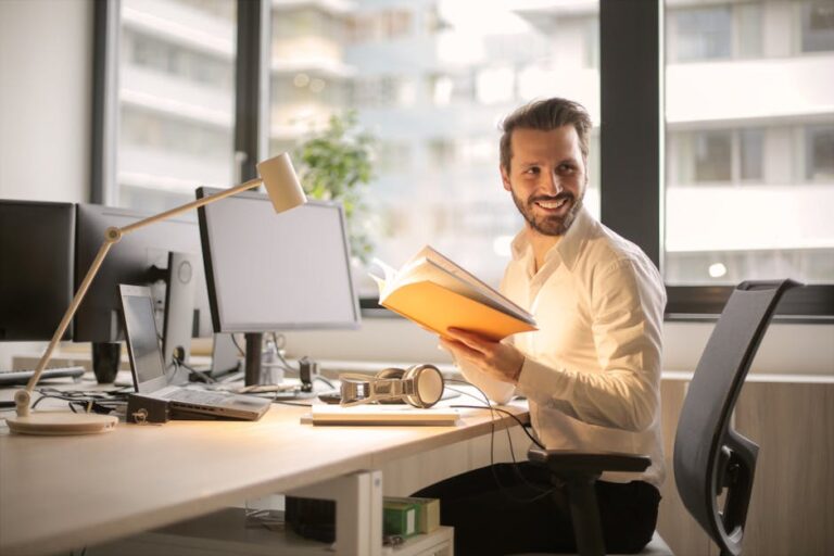 Professional reviewing a notebook at a computer workstation