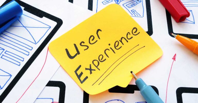 User Experience handwritten on a sticky note beside interface sketches