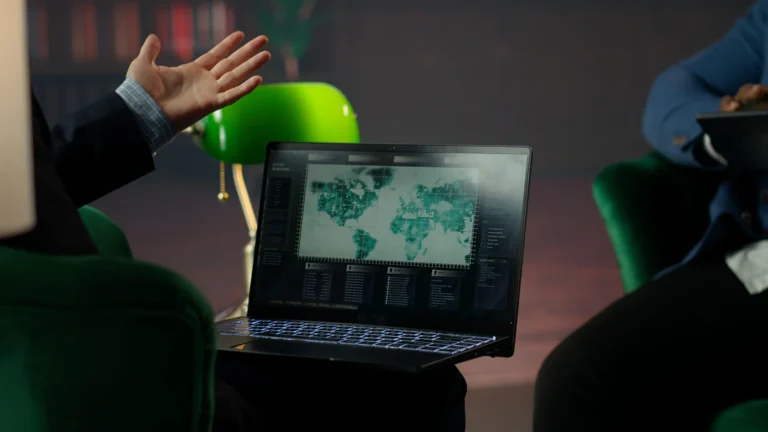 Colleagues discussing a world map displayed on a laptop